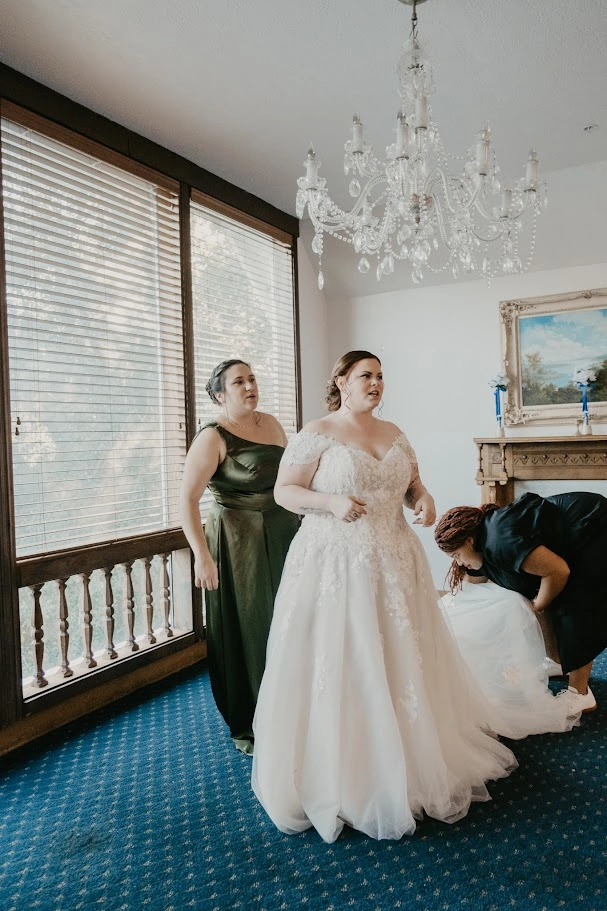 A bride receiving personal support as her wedding gown is adjusted