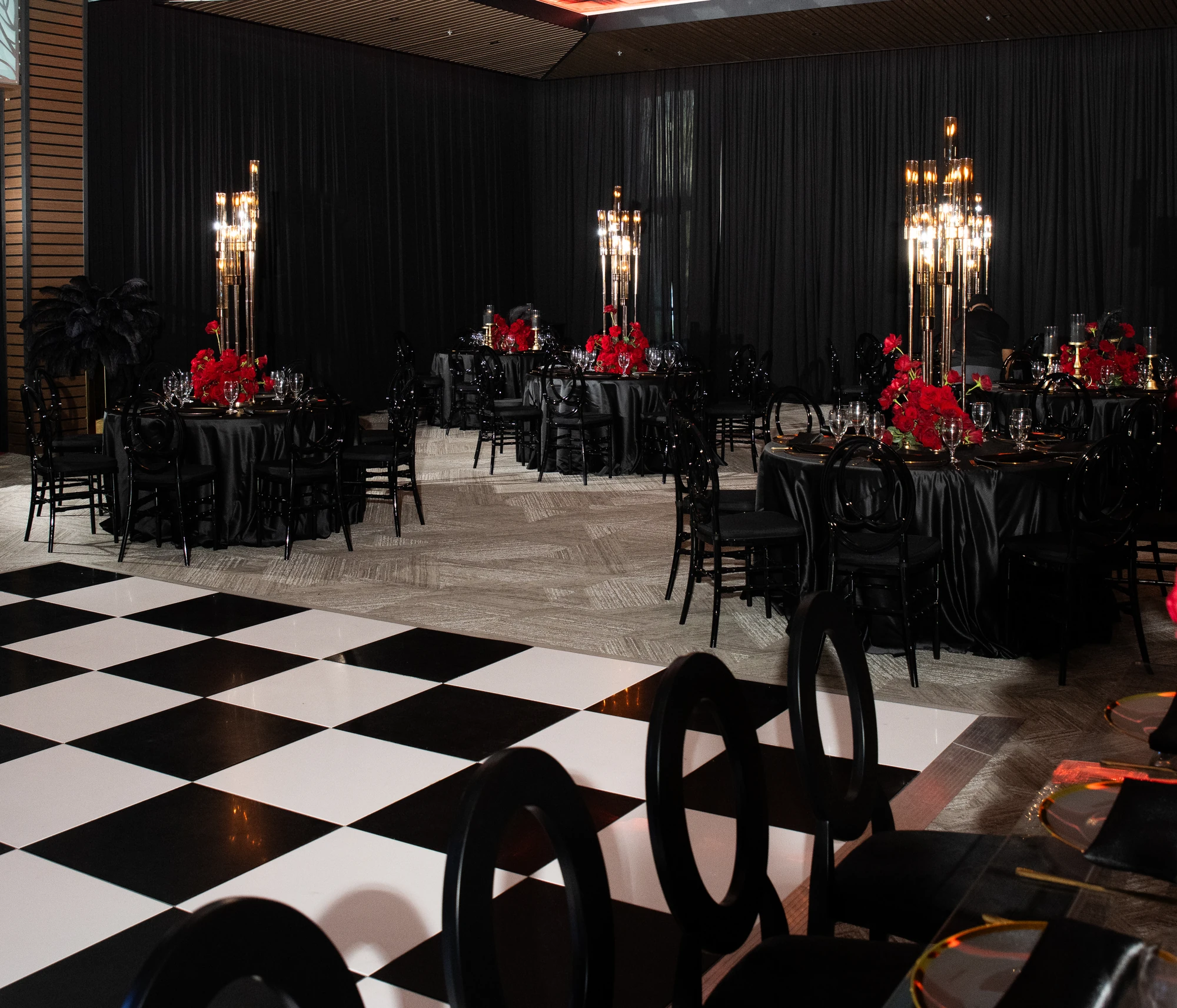 A celebration with black linens, red florals, and candlelight