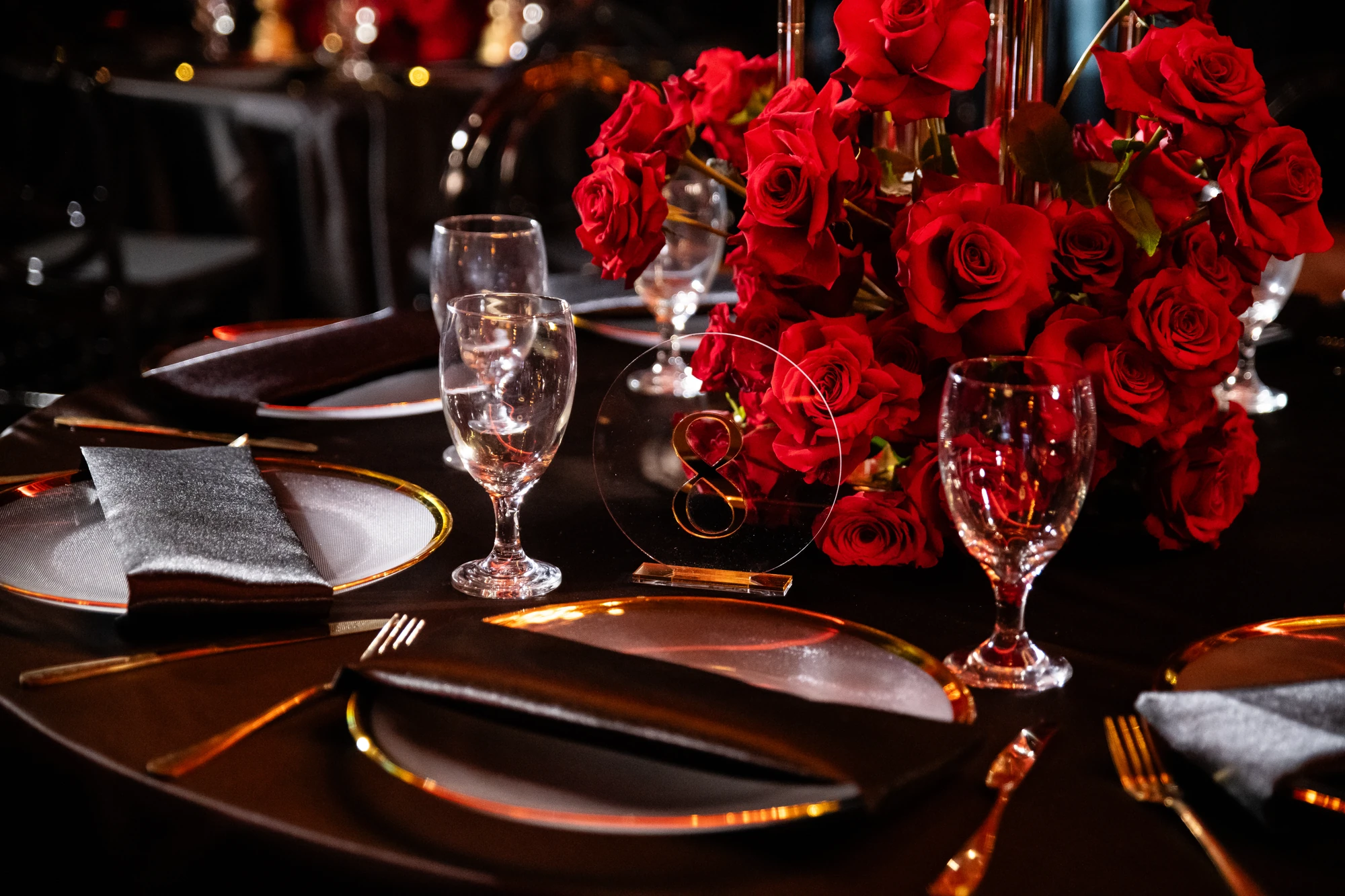 Red roses, black linens, and gold-rimmed table settings