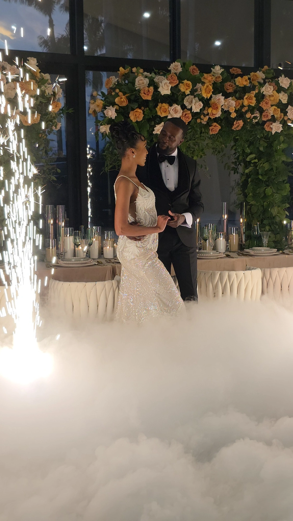 A couple beneath a floral installation with candlelight and spark effects