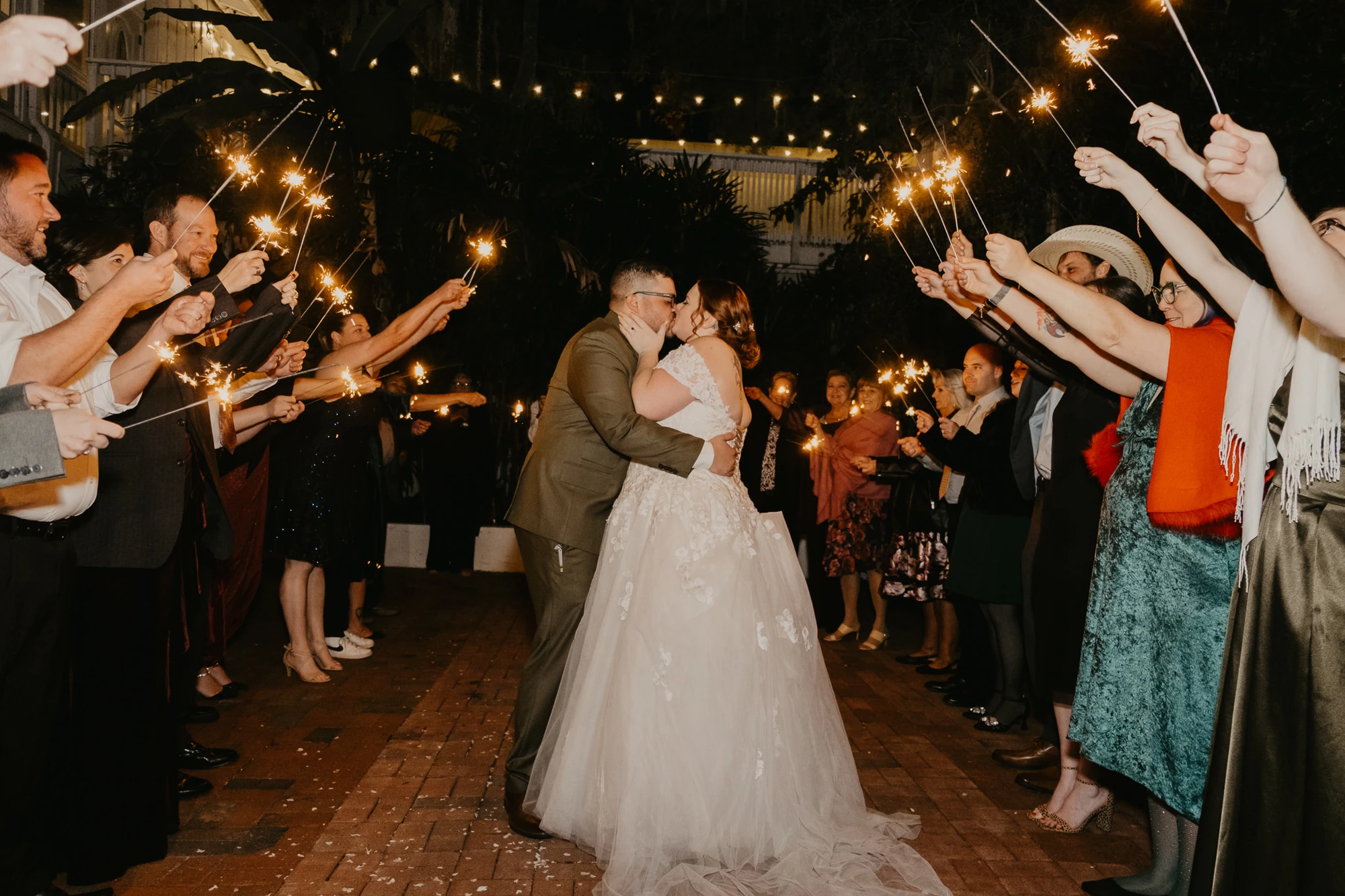 A newlywed couple celebrating their evening exit beneath sparklers