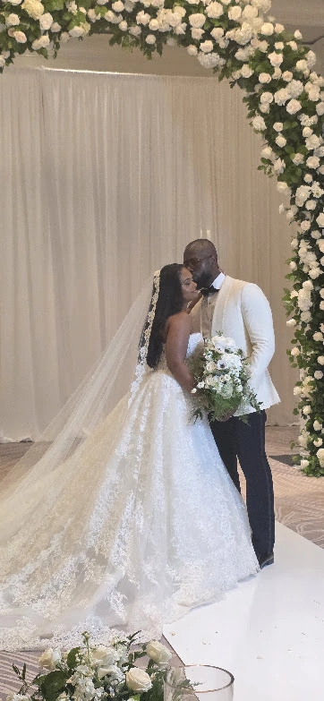 A newlywed couple beneath an arch of white roses