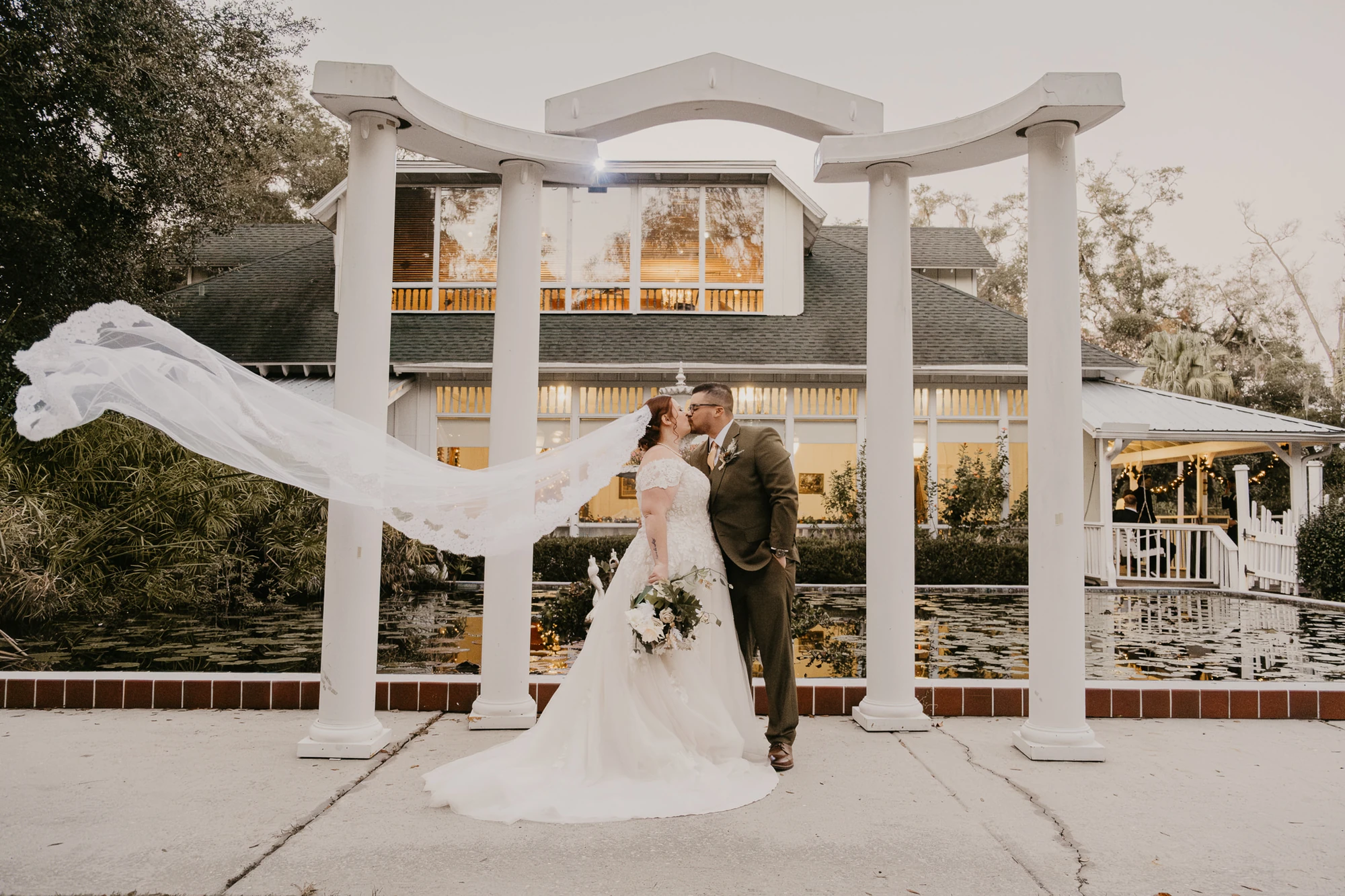 A newlywed couple together beneath a white pergola